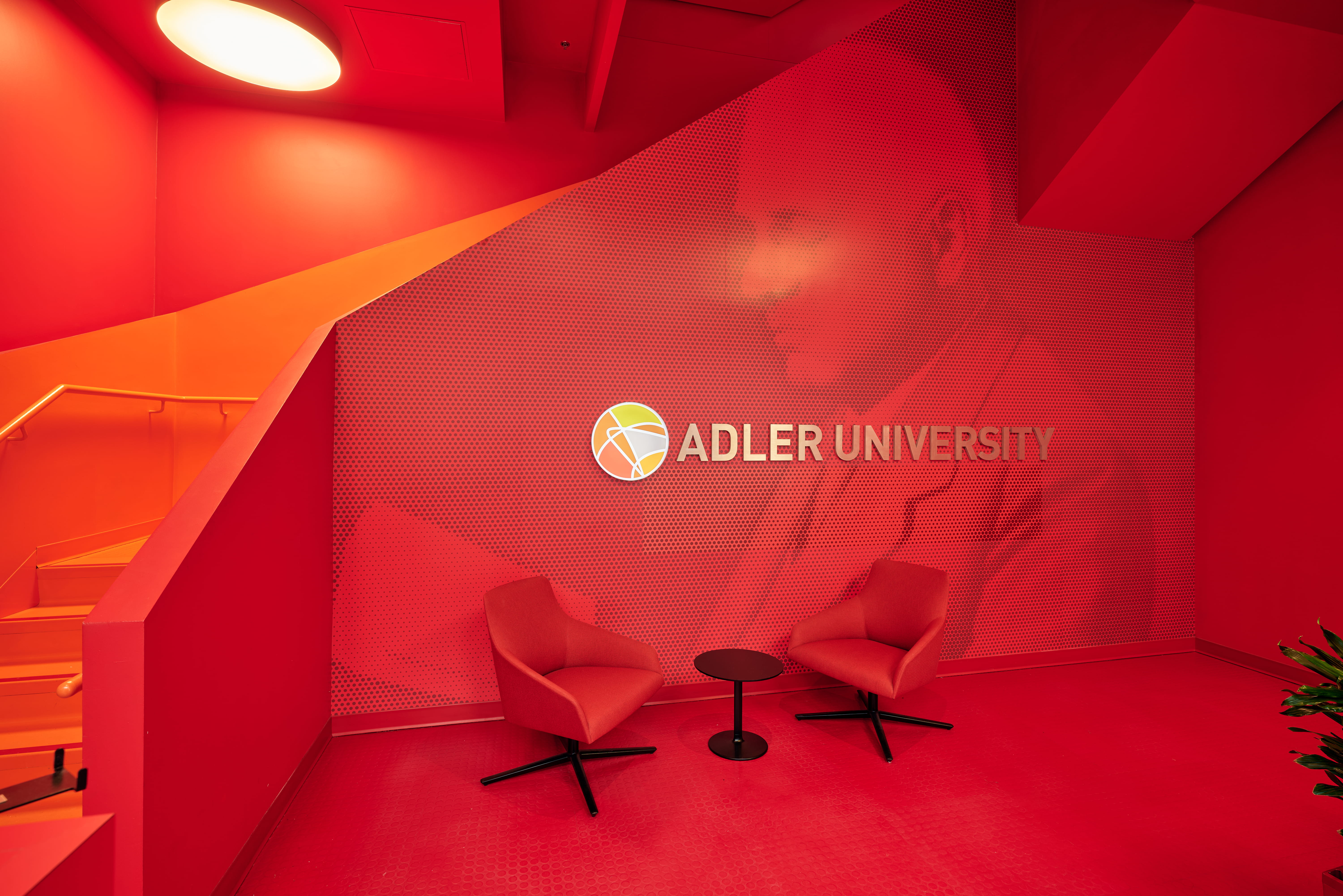Adler University with globe word mark against bright red background -- image originally from the Vancouver Campus. 